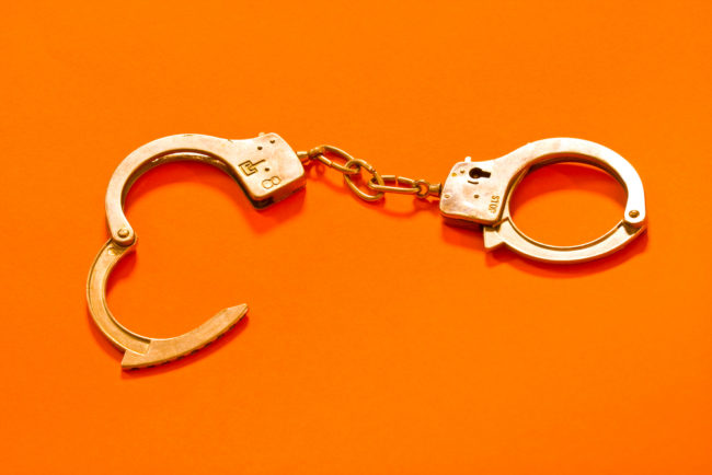 Open,Metal,Handcuffs,On,The,Orange,Background
